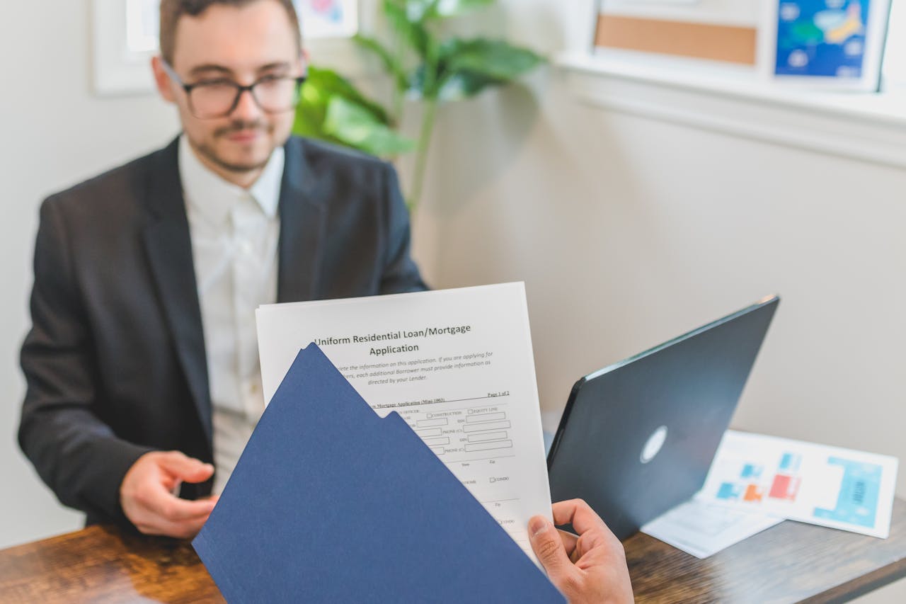 Mortgage broker and client discussing loan application with documents on table.